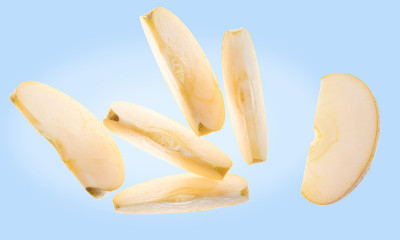 黄苹果切片坠落(鸡腿，鸡腿，苹果)。品种混合金美味和Pippin Tramchard。前视图。浅蓝色
