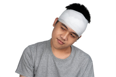 亚洲男孩脑震荡，头部受伤。一个头上缠着绷带的男孩。一个头部受伤的少年。在学校解剖头皮。