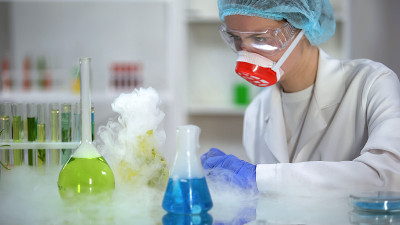 实验室工作人员检查装有有色液体的冒烟烧瓶的反应