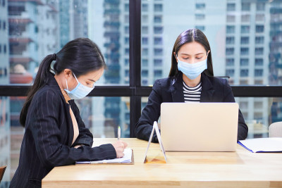 亚洲商务女性在社交距离和新常态政策下，在共同工作空间中一起工作，在新冠肺炎期间在商务办公室工作场所佩