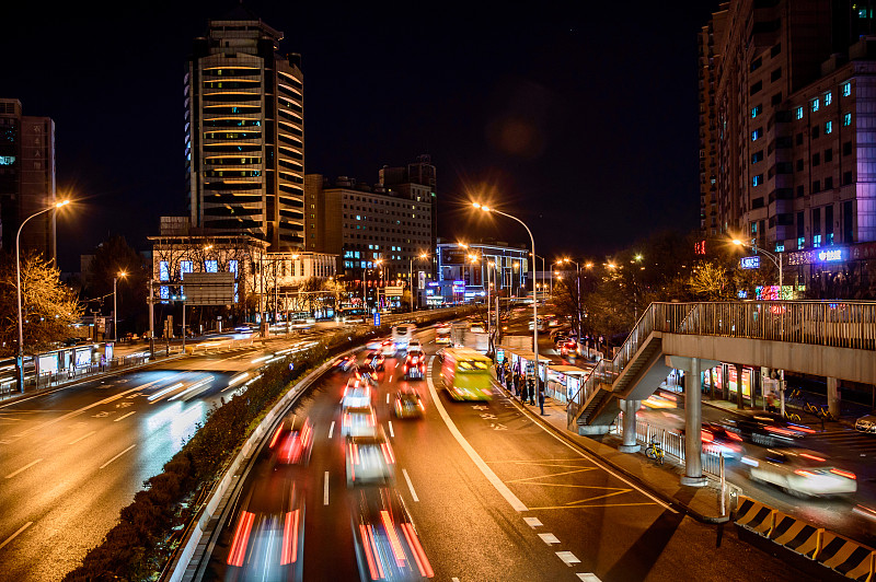 北京的夜晚，汽车行驶在繁忙的城市道路上。