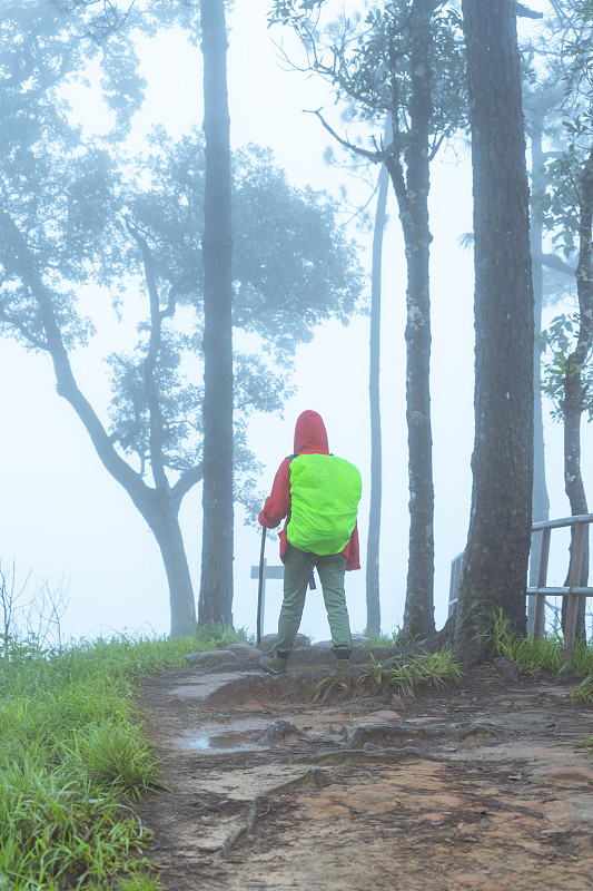 背包客在大雨后以雾为背景的山顶悬崖徒步旅行