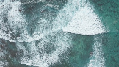 在黄金时刻飞过海洋。巨大的波浪在海洋中激起泡沫和水花。冲浪者乘风破浪。夏威夷瓦胡岛上的太平洋海水的蓝
