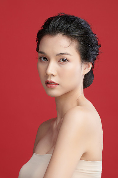 美丽年轻的亚洲女人与干净的新鲜的皮肤在红色背景，面部护理，面部治疗，美容和水疗中心，亚洲妇女肖像。