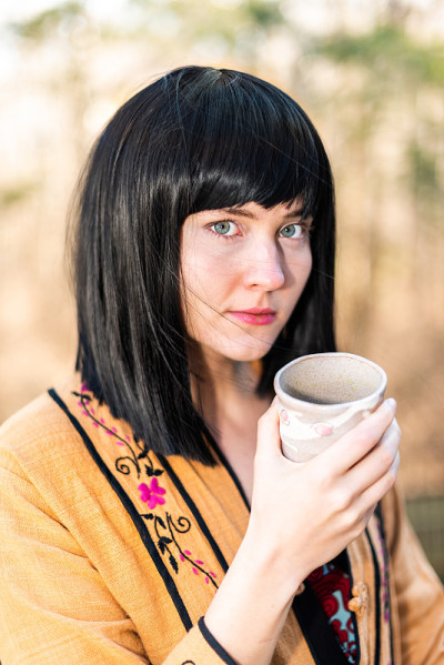 女人拿着茶杯面对严肃的特写在后院花园喝与女孩和黑发