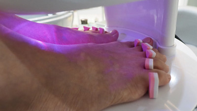 脚Spa。在水疗店的肥皂水机里，女人光脚按摩。女人的脚进入脚浴在热水手持式。在水疗沙龙用脚油按摩。放
