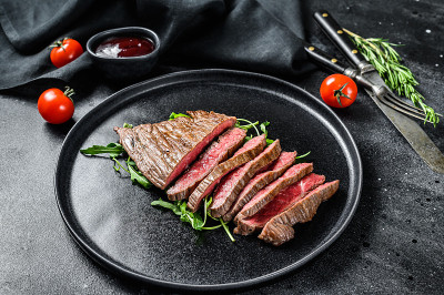 烤和切平铁牛排。大理石牛肉肉。黑色背景。俯视图