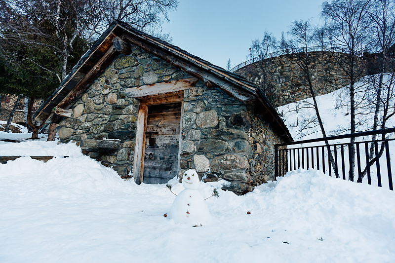 小雪人在石屋前。冬天在El Tarter村。预览效果