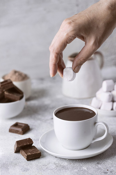 手把棉花糖放进热巧克力杯。传统冬季饮品概念