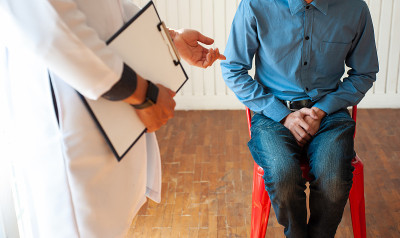 医生拿着文件来诊断男性病人的症状。男性健康问题概念。