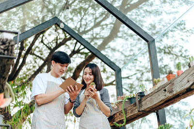 女人拿着仙人掌，男人在书上写便条。爱的夫妇喜欢与达顿仙人掌爱好。