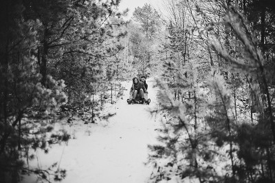 微笑和幸福的夫妇享受在森林或城市公园滑雪下山。两个年轻人:一个男人和一个女孩在雪地上滑木制雪橇。黑白