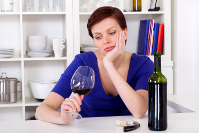 年轻悲伤沉思的女人喝着一杯红酒