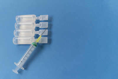蓝色背景下安瓿生理血清注射器。医学测试。