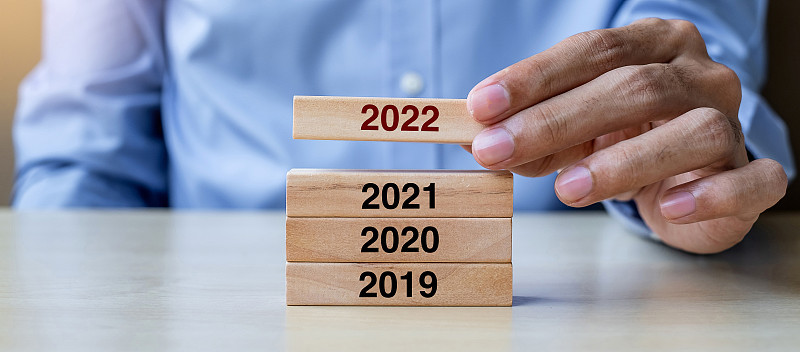 商人手拉2022木制积木在桌子的背景上。商业计划，风险管理，决议，战略，解决方案，目标，新年，新年你