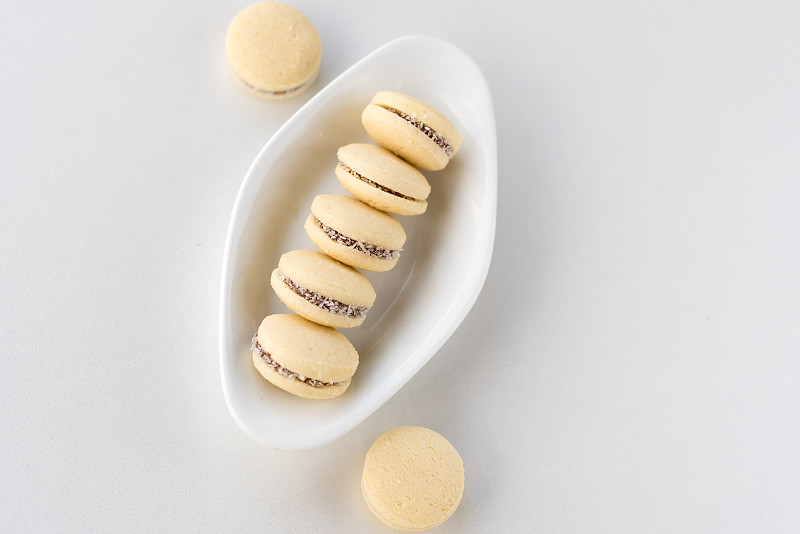 俯视图Alfajores，焦糖酥饼和椰子卷。白色盘子上的阿根廷马卡龙