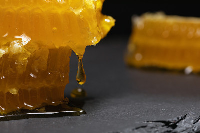 金色破碎的蜂窝片与滴新鲜蜂蜜在模糊的背景