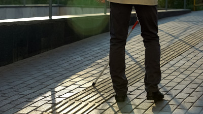 视障人士用手杖在盲人专用的路面上行走