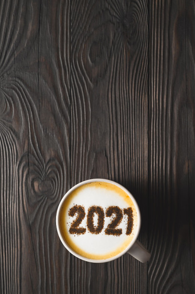 黑色木桌上的咖啡杯上泡沫表面的2021号。食品创意概念。