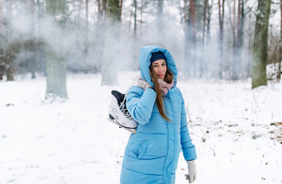 在雪地里拿着溜冰鞋的女人。