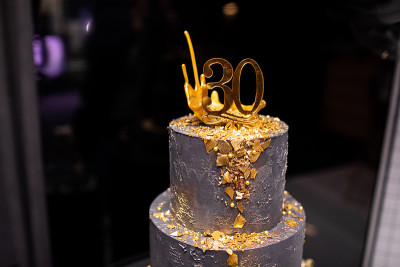 30周年庆典用金色装饰的双层黑蛋糕。糖的生日