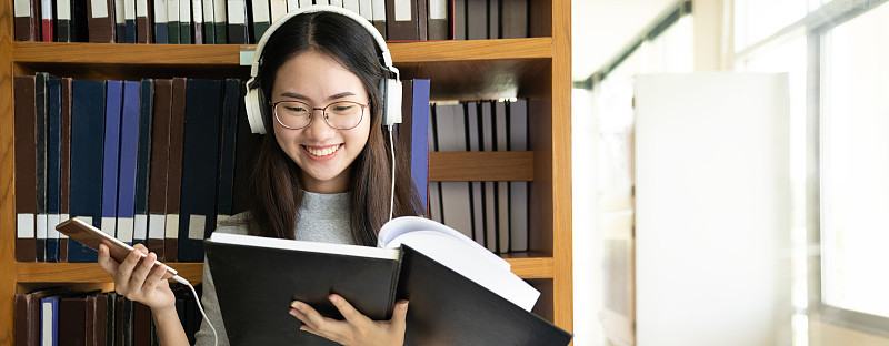 回到学校教育知识学院的大学理念，美丽的女大学生抱着她的书微笑着站在图书馆，学习和教育的理念