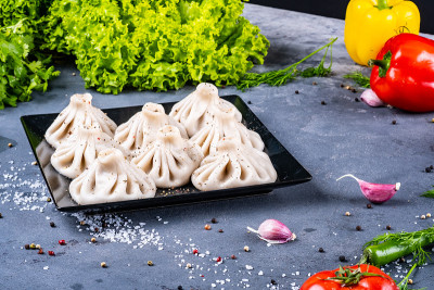 格鲁吉亚食物Khinkali与香菜在黑色盘子与蔬菜复制空间