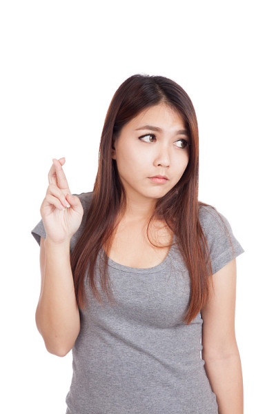 年轻的亚洲女子交叉她的手指看别处