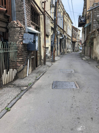 美丽的旧棕色破旧的三层楼的房子的建筑在一个鹅卵石狭窄的街道上，有窗户和阳台，贫民窟的露台在老城区的城