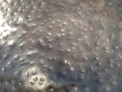 Bent metal with dents. Close-up of a bronze surfac