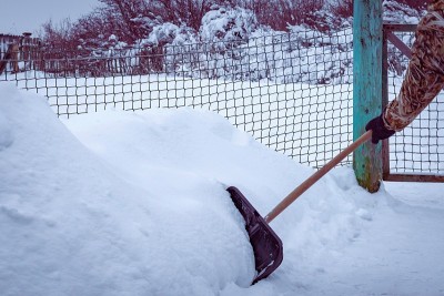 木柄黑色塑料雪铲在雪堆的背景上。