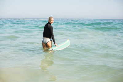 穿着潜水服的女人在海滩上拿着冲浪板