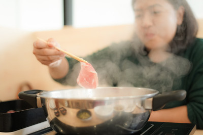 亚洲妇女用沸腾的锅煮猪肉
