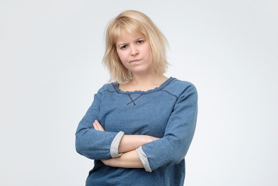 不满意的金发女人站着双臂交叉