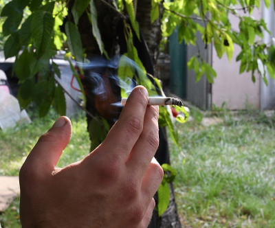 吸烟的男性手指的特写与室外后院的背景
