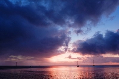令人惊叹的太平洋热带日落海景与帆船在远处