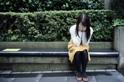 一个亚洲女人失望地坐在户外。