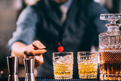 酒保准备老式鸡尾酒，装饰樱桃。葡萄酒过滤图像