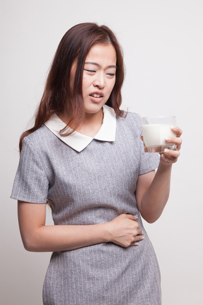 一位亚洲妇女喝了一杯牛奶后胃痛。
