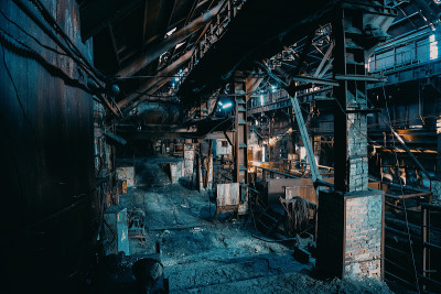 大型废弃的冶炼厂车间、机库或仓库内，脏乱、阴森、锈迹斑斑的建筑