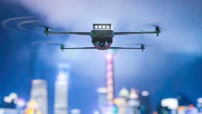飞行的无人驾驶飞机。夜晚的城市作为背景。混合媒体。