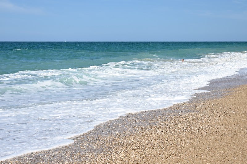 Beach with crystal clear sea and colored pebbles