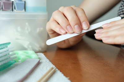 在家里修指甲。妇女的手在家里锯指甲近与美甲组