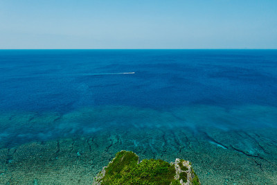 船穿过海洋，靠近珊瑚礁和蓝天