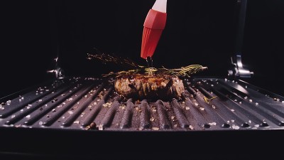 美味多汁的肉排烤制。上等的半熟烤牛肉。电炉，迷迭香，黑胡椒，盐。硅胶烹饪刷。
