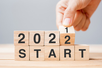 商人手握木立方体和翻转块2021至2022年开始在桌子背景。决心，计划，回顾，改变，目标和新年假期的