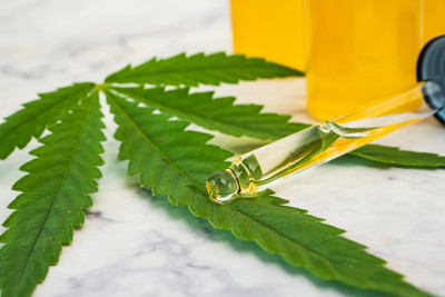 大麻油在小瓶与滴管和绿色叶子在大理石桌上。替代医学概念。