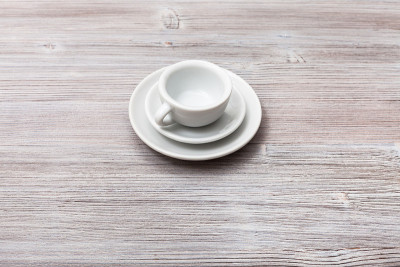 灰褐色板上放着茶托的白色杯子