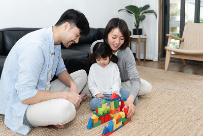 年轻的亚洲妈妈和爸爸正在和他们的女儿一起搭积木