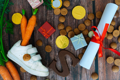 荷兰节日的Sinterklaas背景有儿童鞋、胡萝卜为圣诞老人的马、礼物、传统的蜜饯和巧克力信。平铺